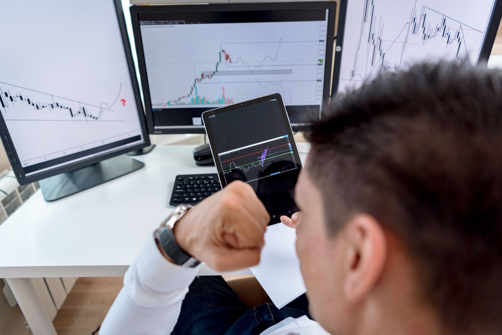 Trader reviewing stock market charts on multiple monitors